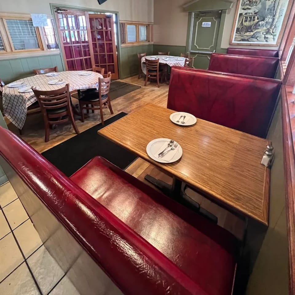Interior of Buffalo Indian Restaurant with red booths, wooden tables, and checkered tablecloths.